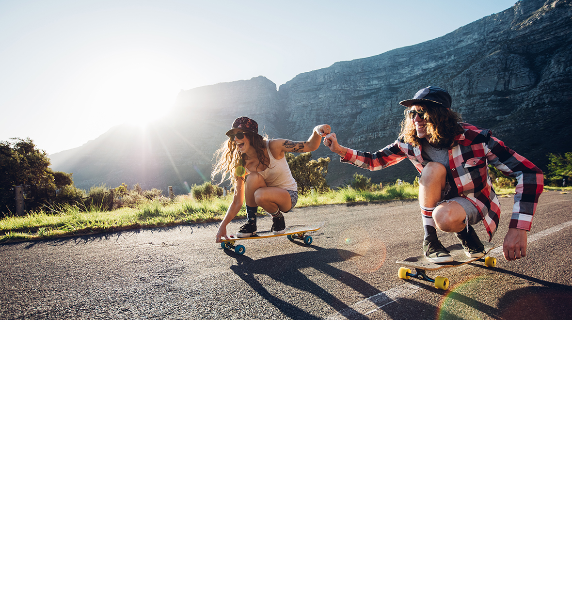 two people on their own skateboards riding together holding hands