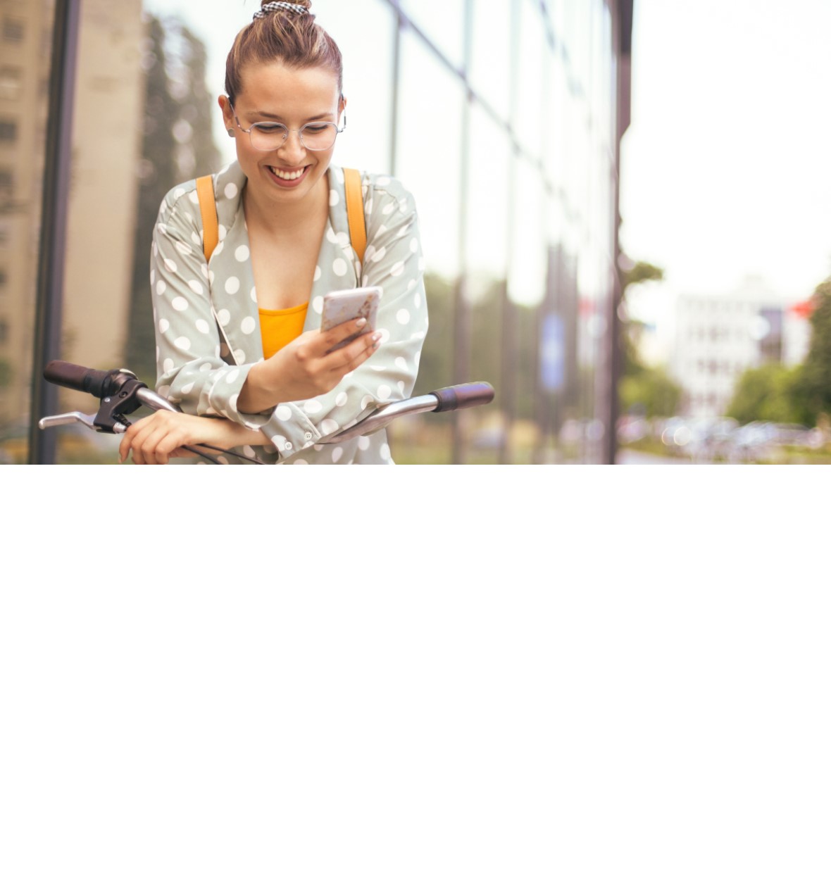 girl outside a building smiling down at her mobile