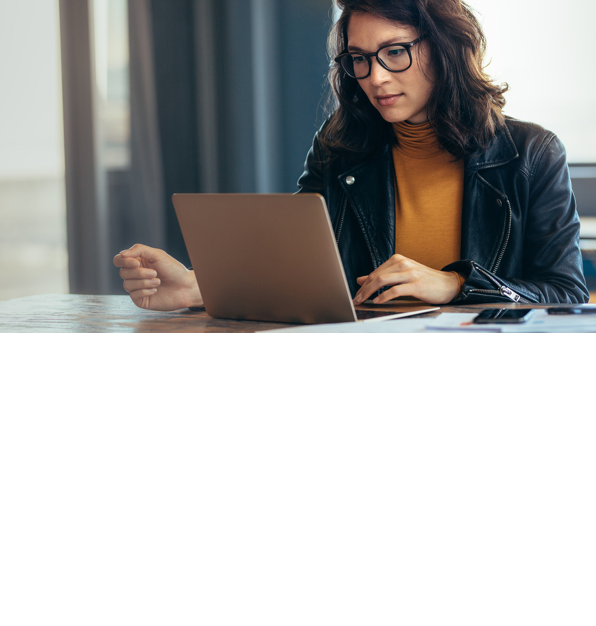 a woman with glasses looking down at the laptop