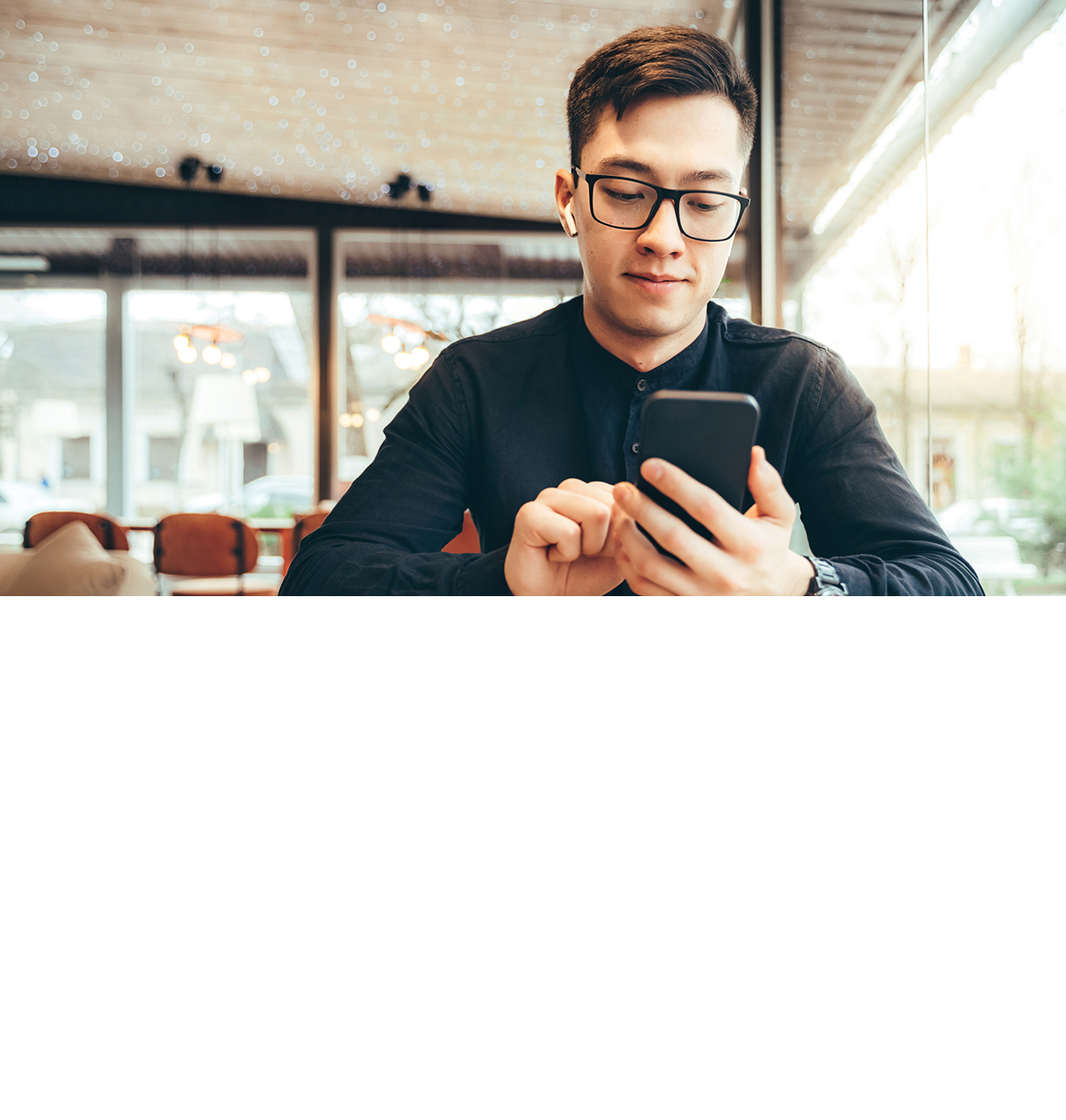 Guy with glasses smiling and looking down at his mobile phone